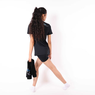 Woman in black athletic outfit holding a black towel, demonstrating yoga or fitness exercise